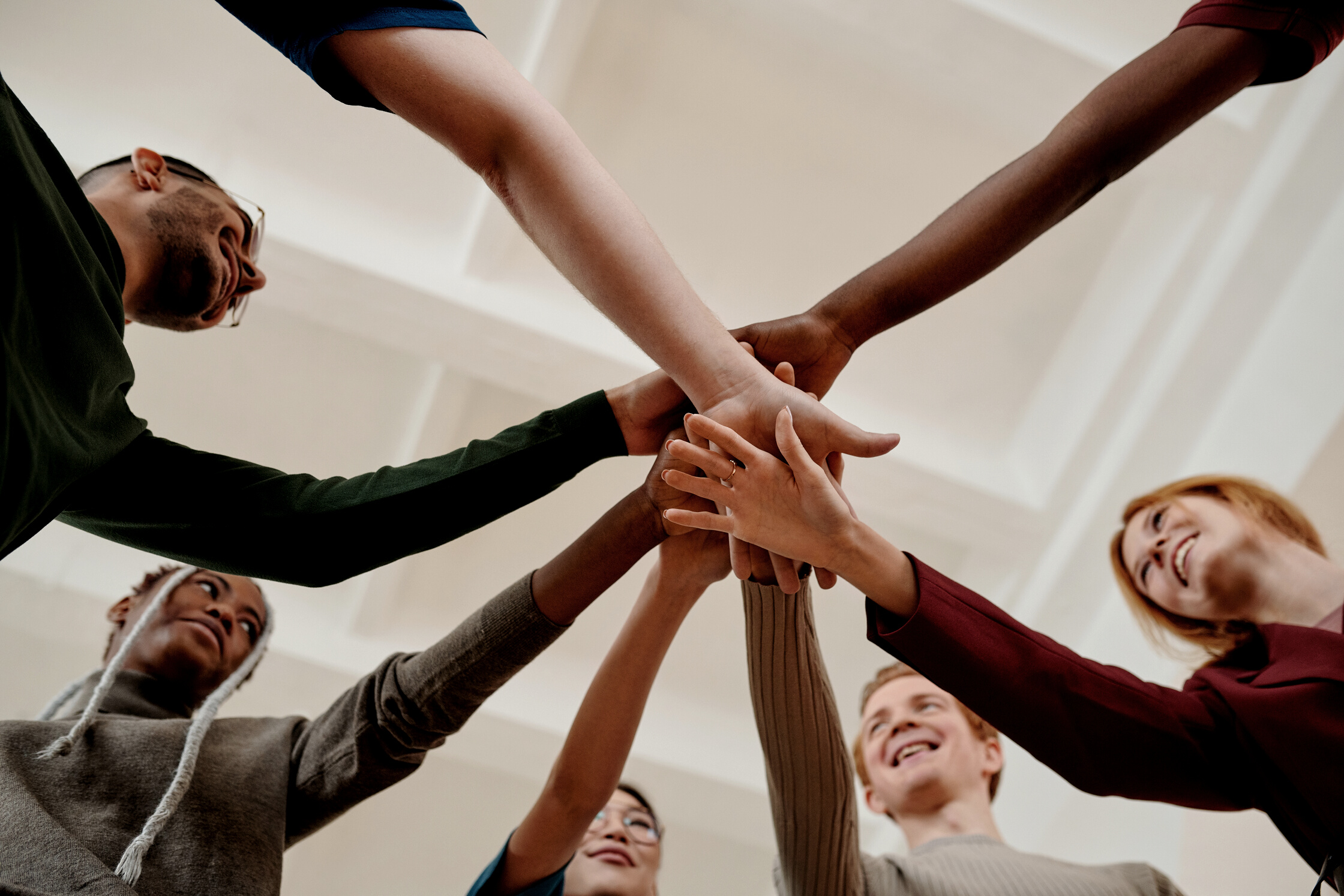 People Putting Hands Together in Act of Motivation and Smiling 